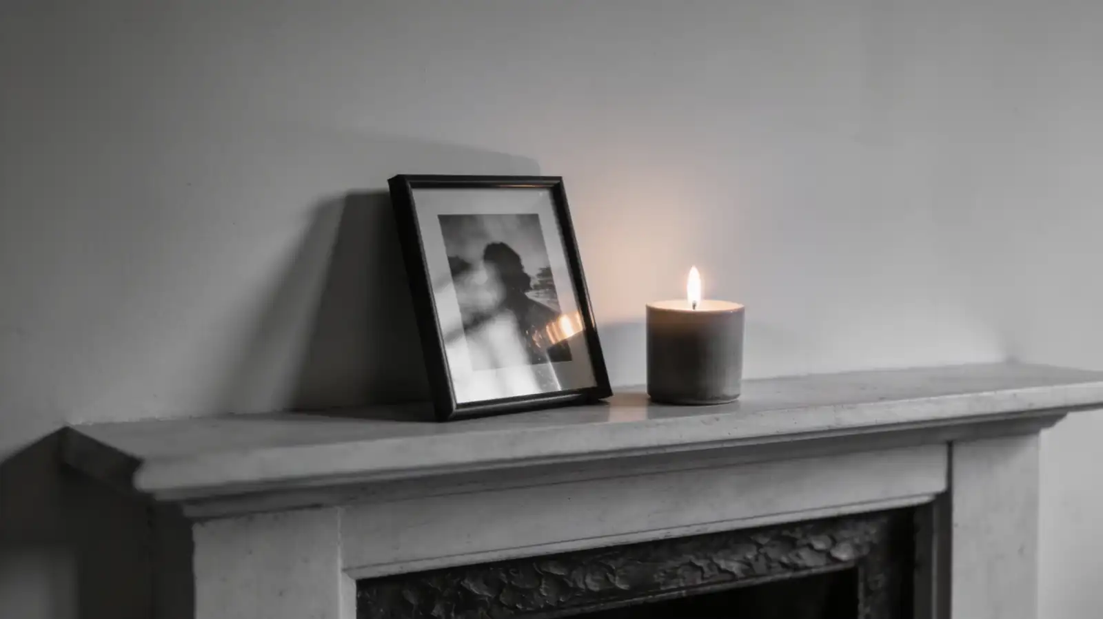 A framed photo on a fireplace mantle with a candle beside it — a memorial tribute